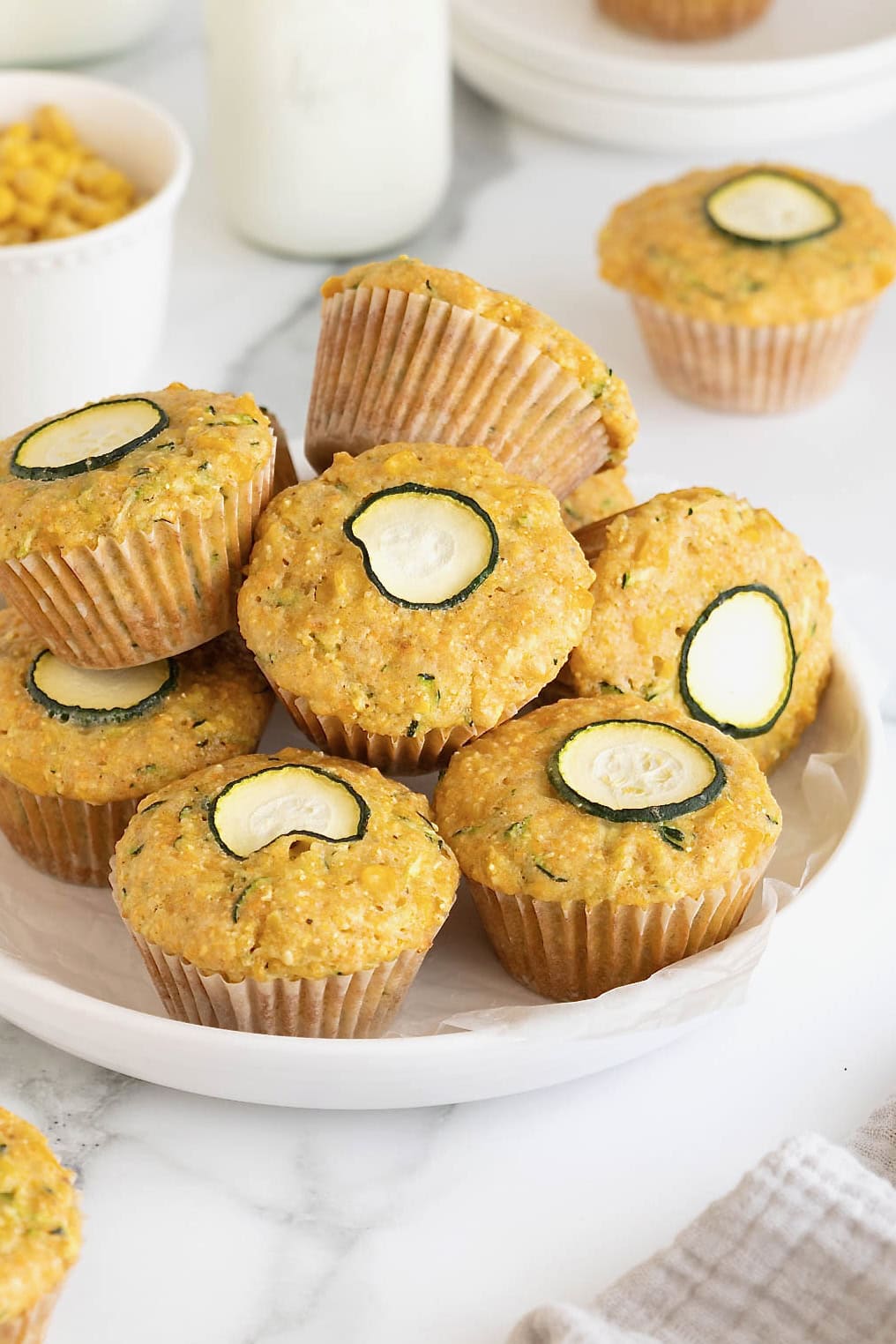 A pile of zucchini corn muffins on a rimmed white plate.