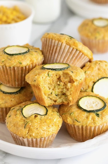 A pile of zucchini corn muffins on a large white rimmed plate.