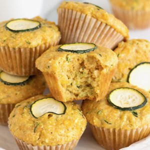 A pile of zucchini corn muffins on a large white rimmed plate.