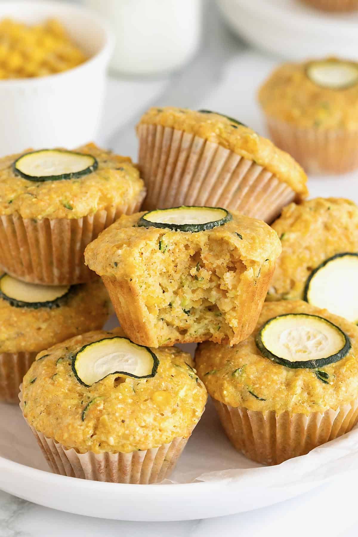 A pile of zucchini corn muffins on a large white rimmed plate.