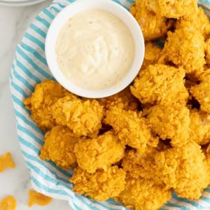 A plate of goldfish chicken nuggets next to a small white dish of ranch dressing.