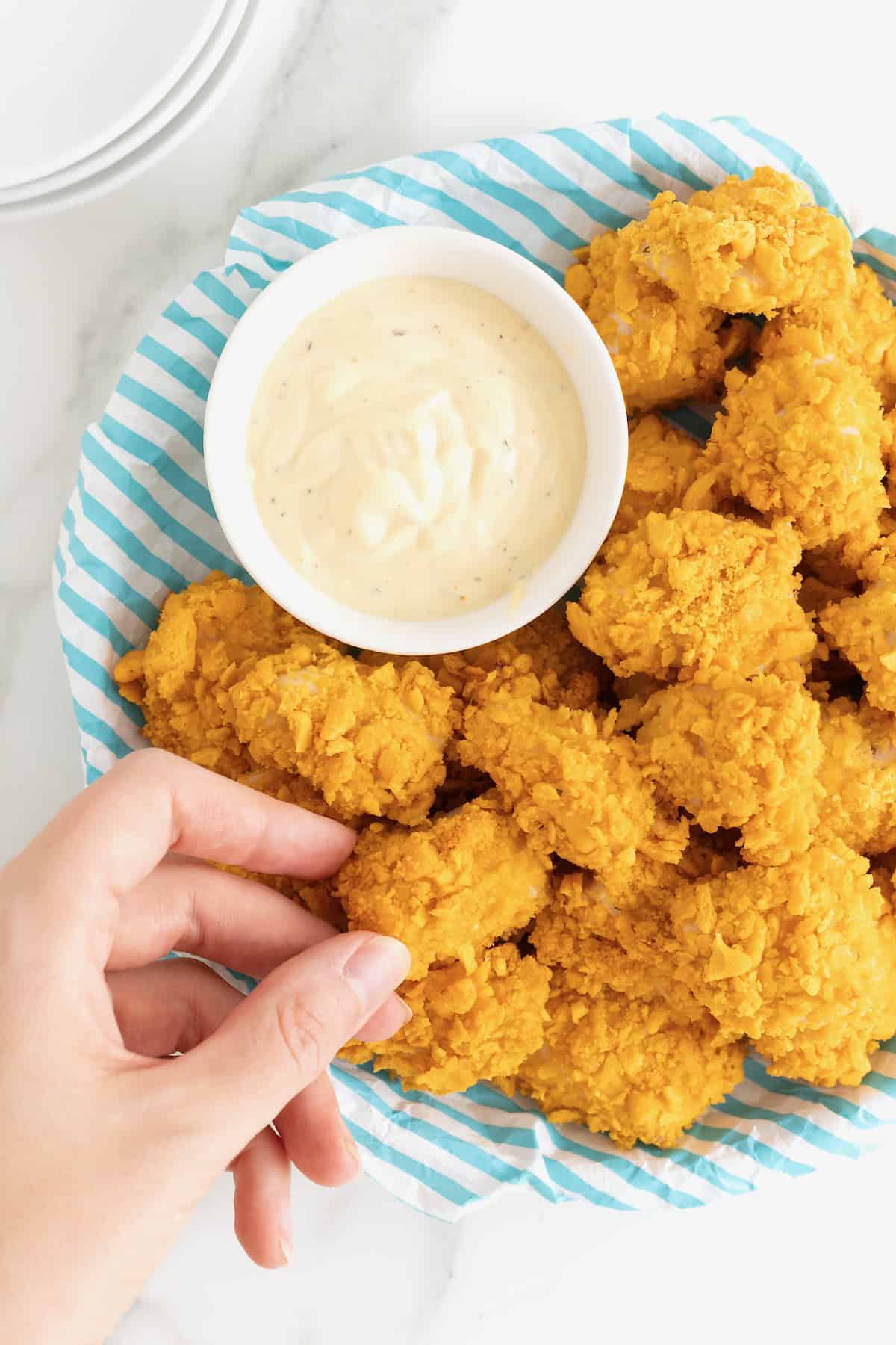 A plate of goldfish chicken nuggets next to a small white dish of ranch dressing.