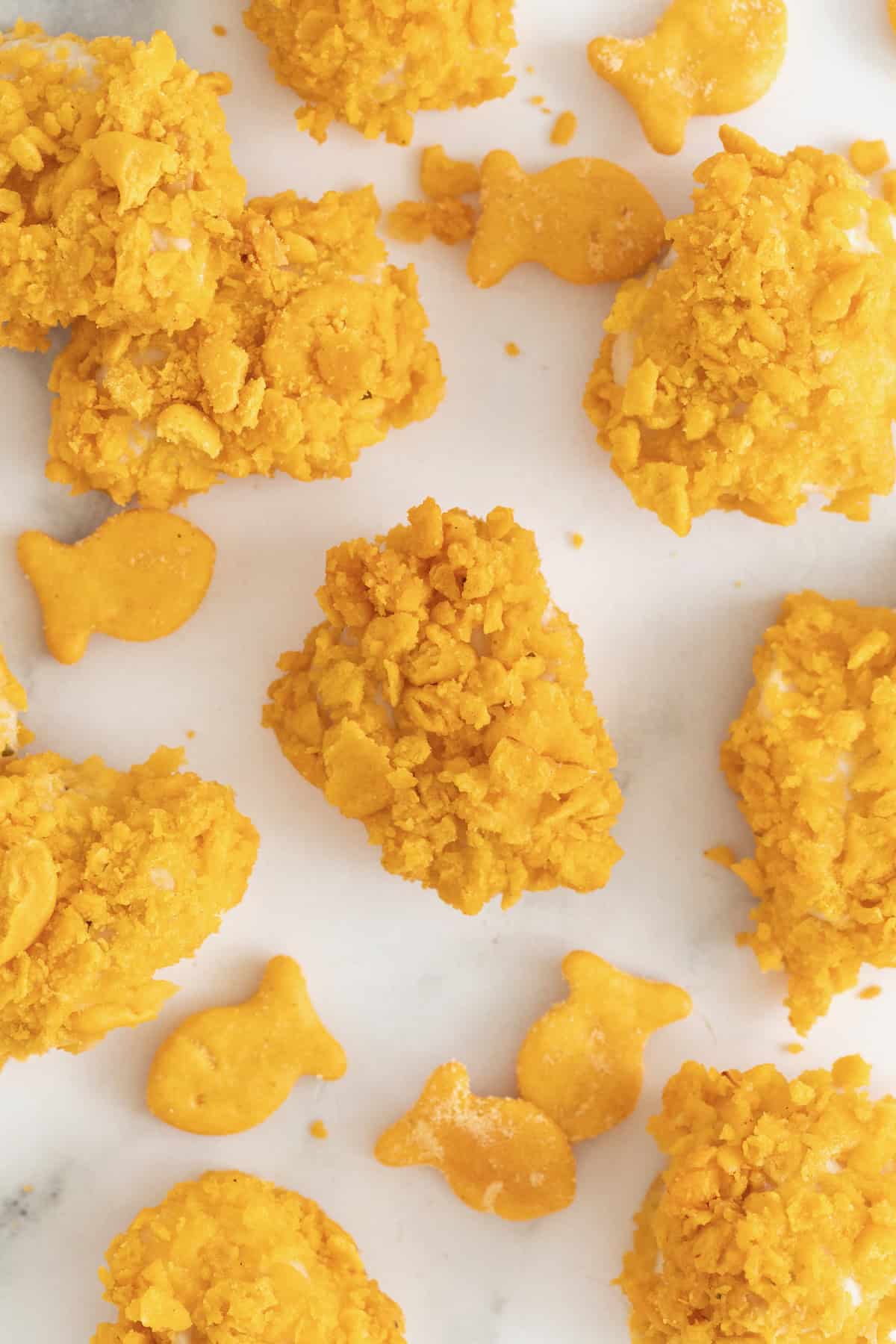 Goldfish chicken nuggets scattered on a white marble counter with several Goldfish crackers.