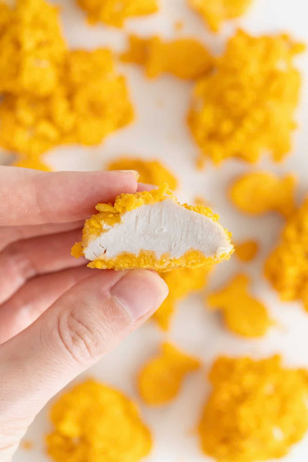 A hand holding a Goldfish chicken nugget bit in half.