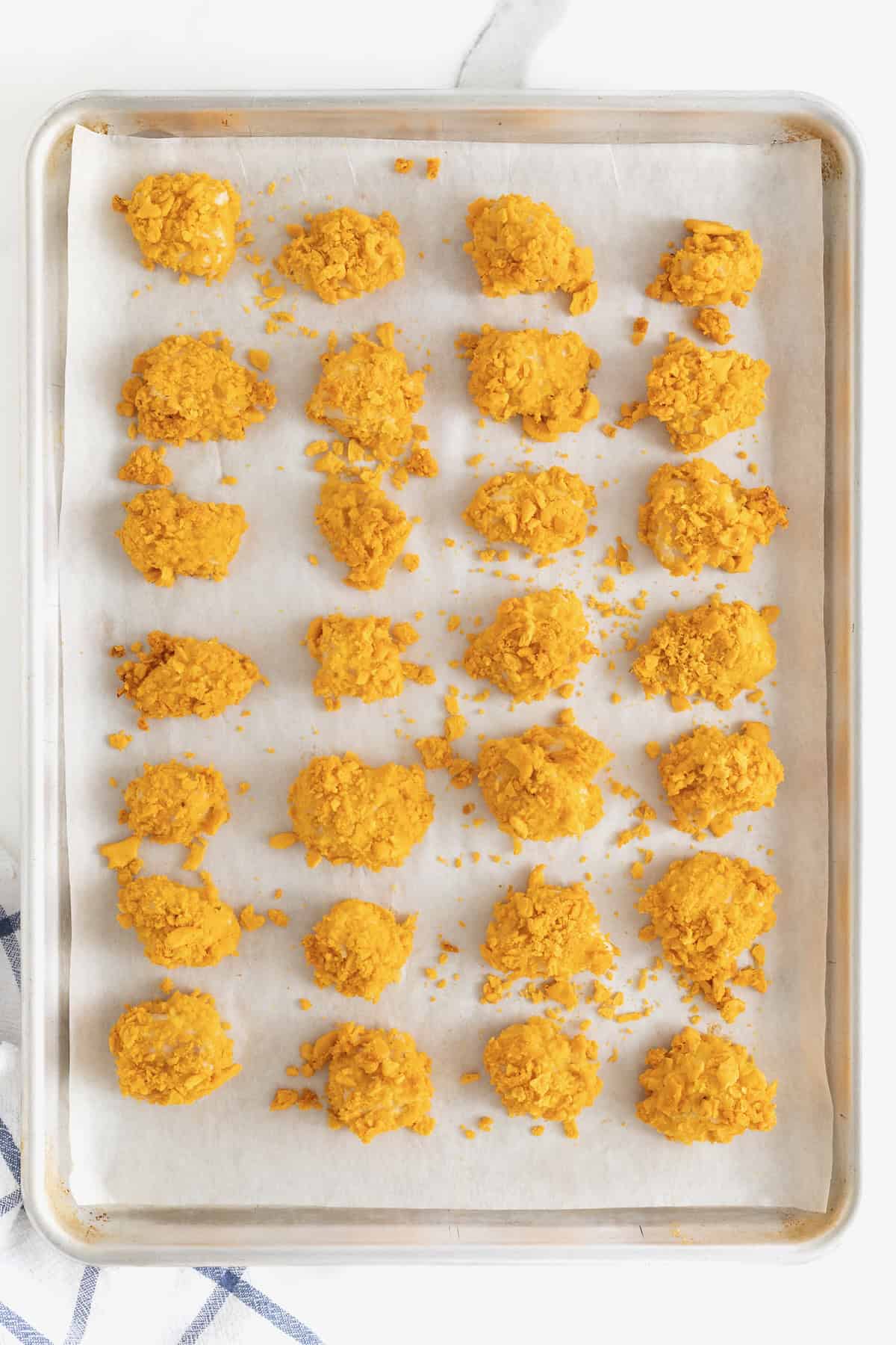 28 Goldfish Chicken nuggets in even rows on a parchment lined aluminum baking sheet.