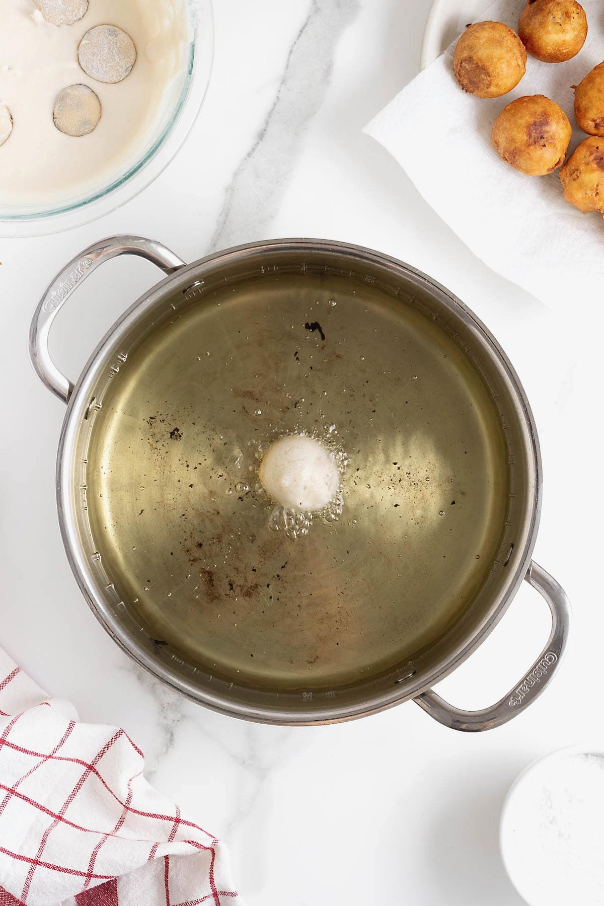A large frying pan of oil with a single battered cookie dough ball in it.