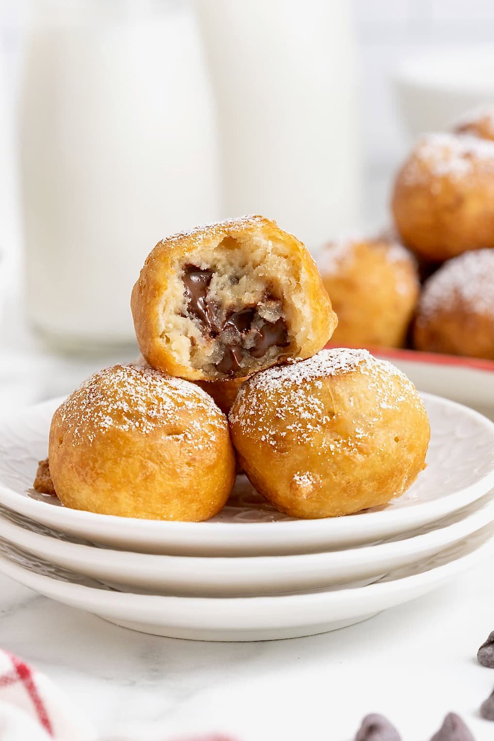 Three deep fried cookie dough bites on a small white plate.