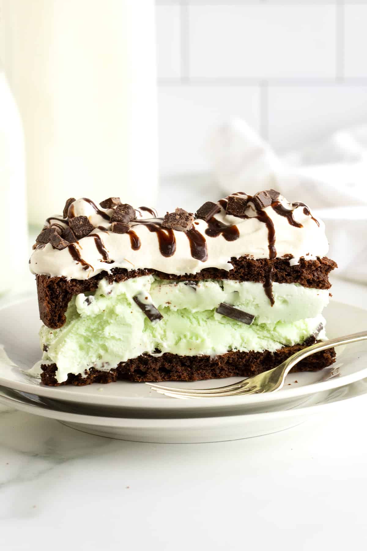 Mint chocolate chip ice cream sandwiched between chocolate cake layers and topped with whipped topping, chocolate sauce, and chopped Andes mints.