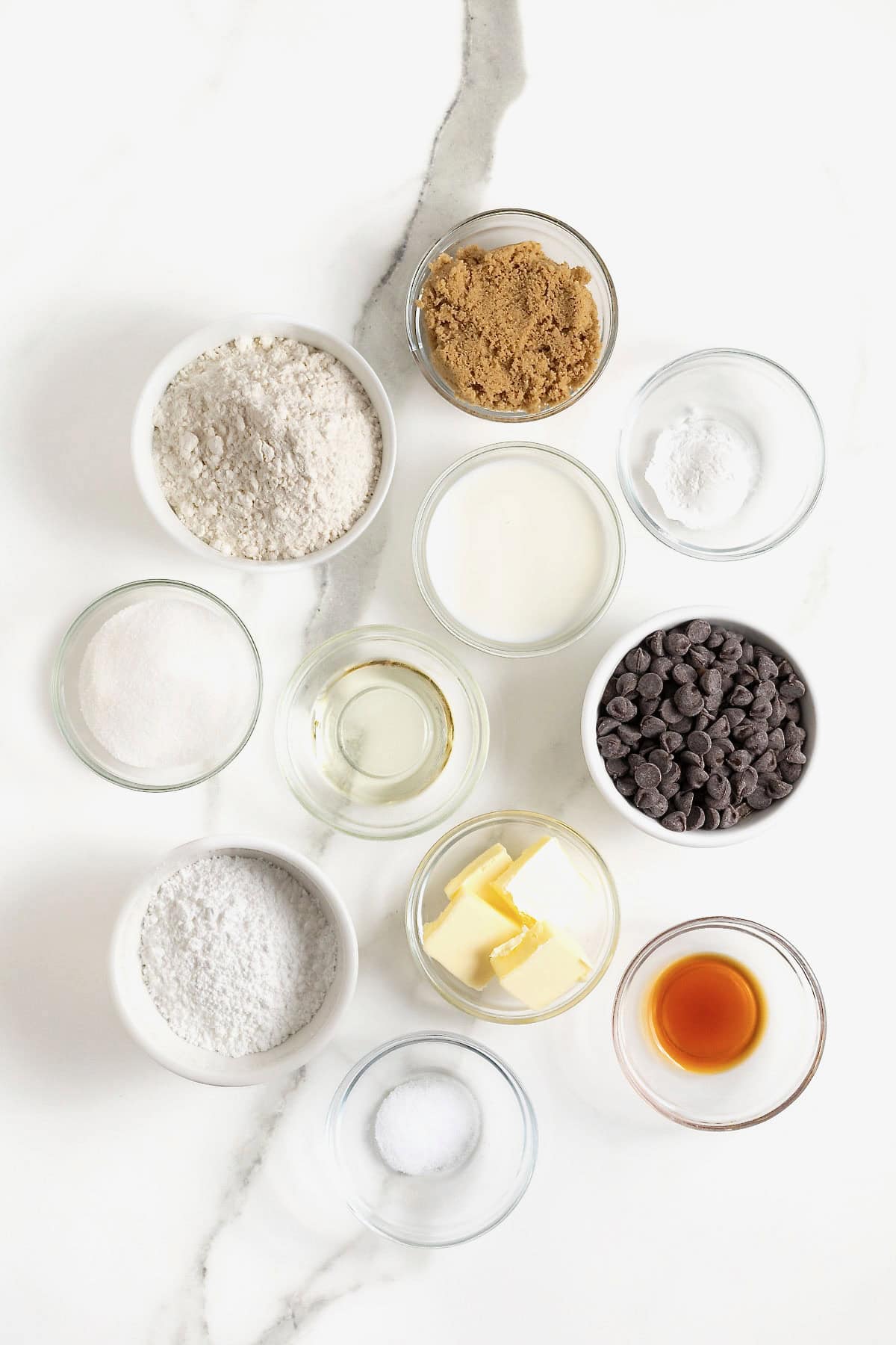 Ingredients to make fried cookie dough in small glass dishes on a white marble counter.