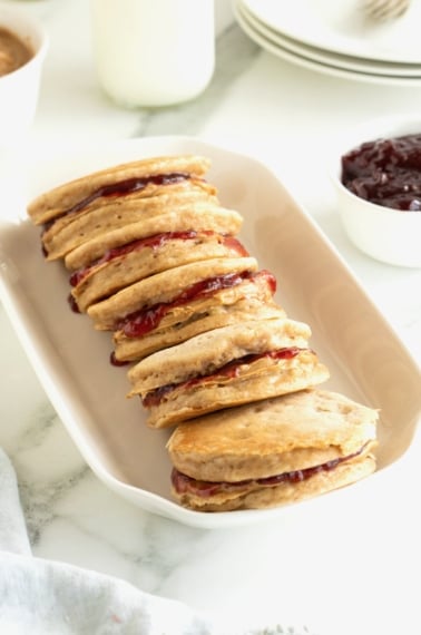 Five pancake sandwiches in an oblong white serving dish.