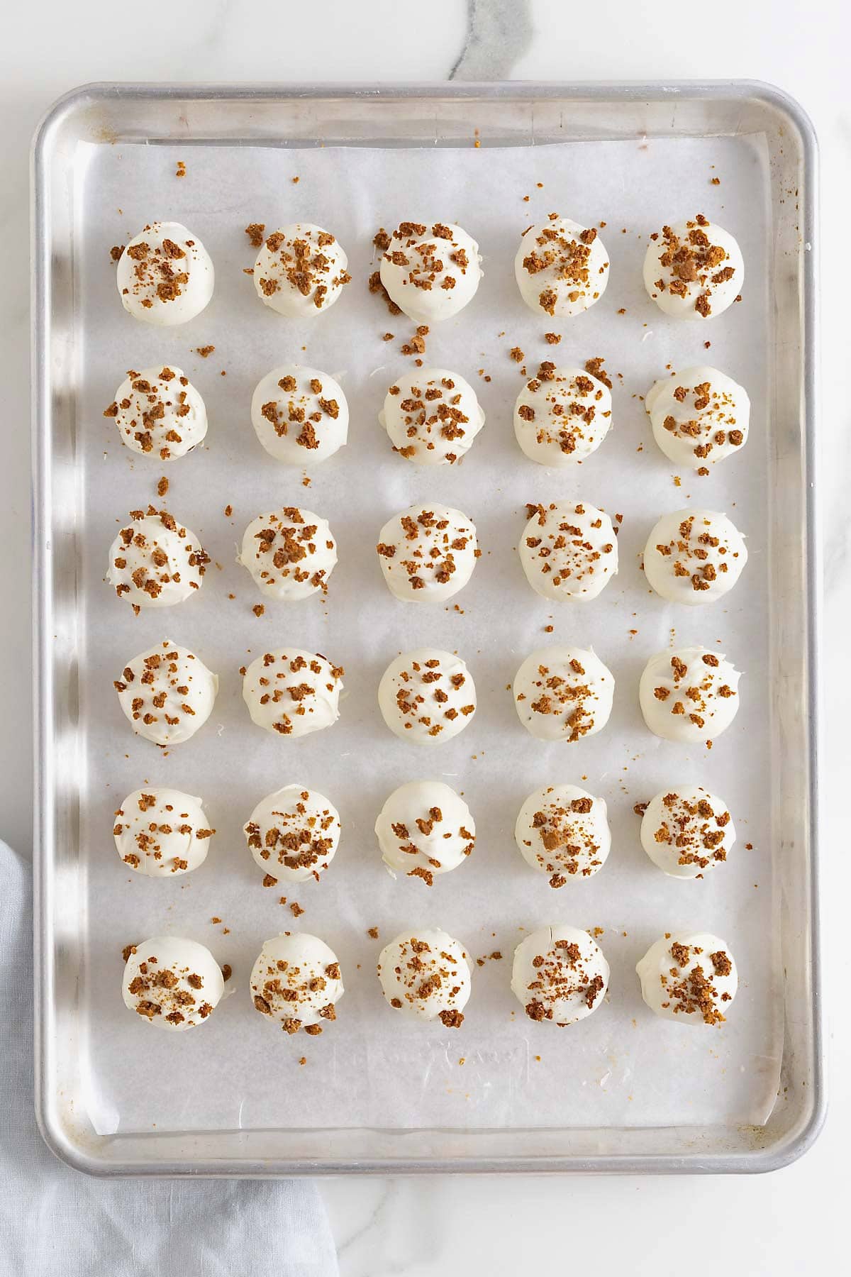 Pumpkin cake balls on a parchment-covered aluminum baking sheet.