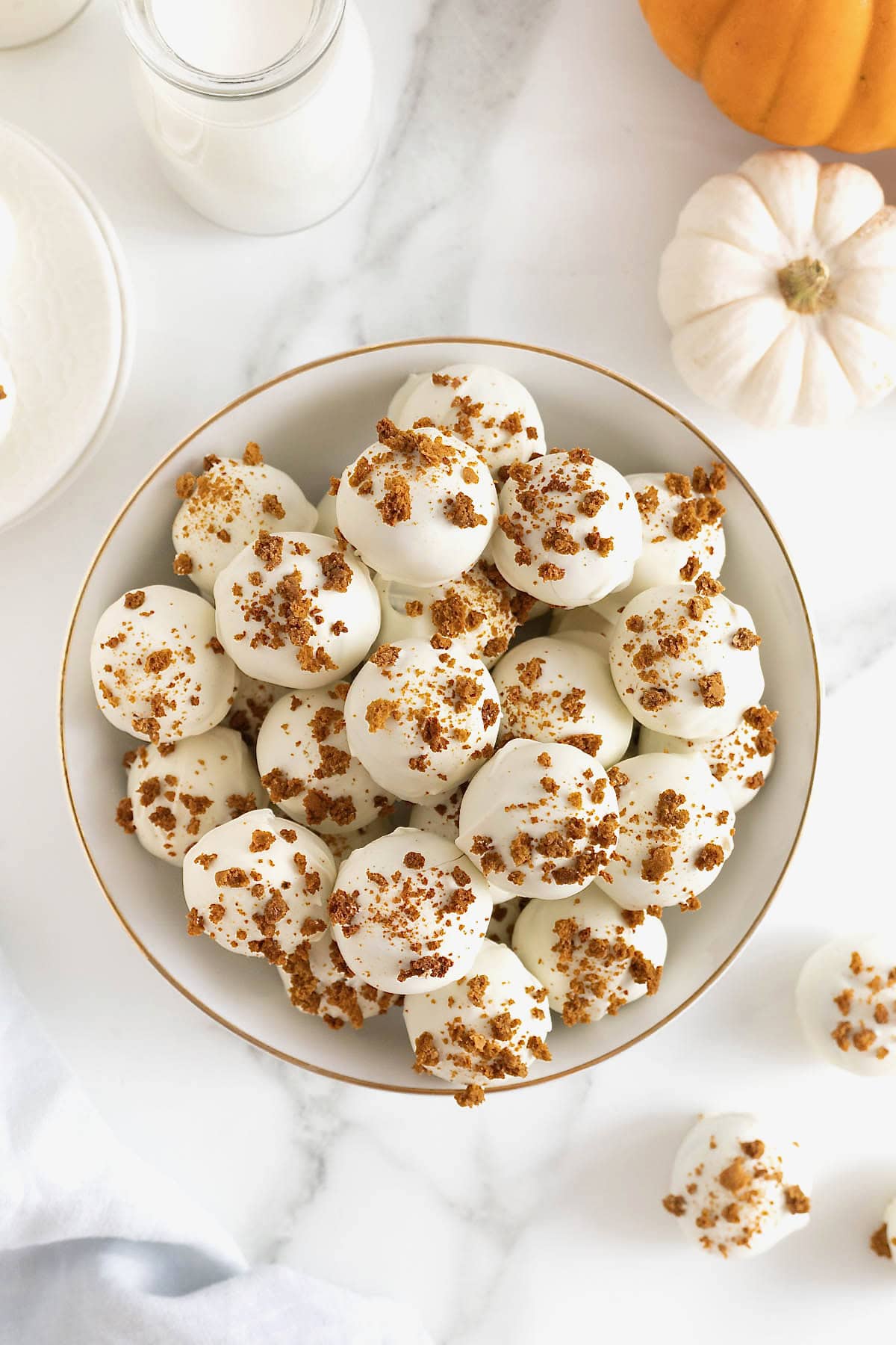 A large white gold-rimmed serving dish filled with pumpkin spice cake balls.