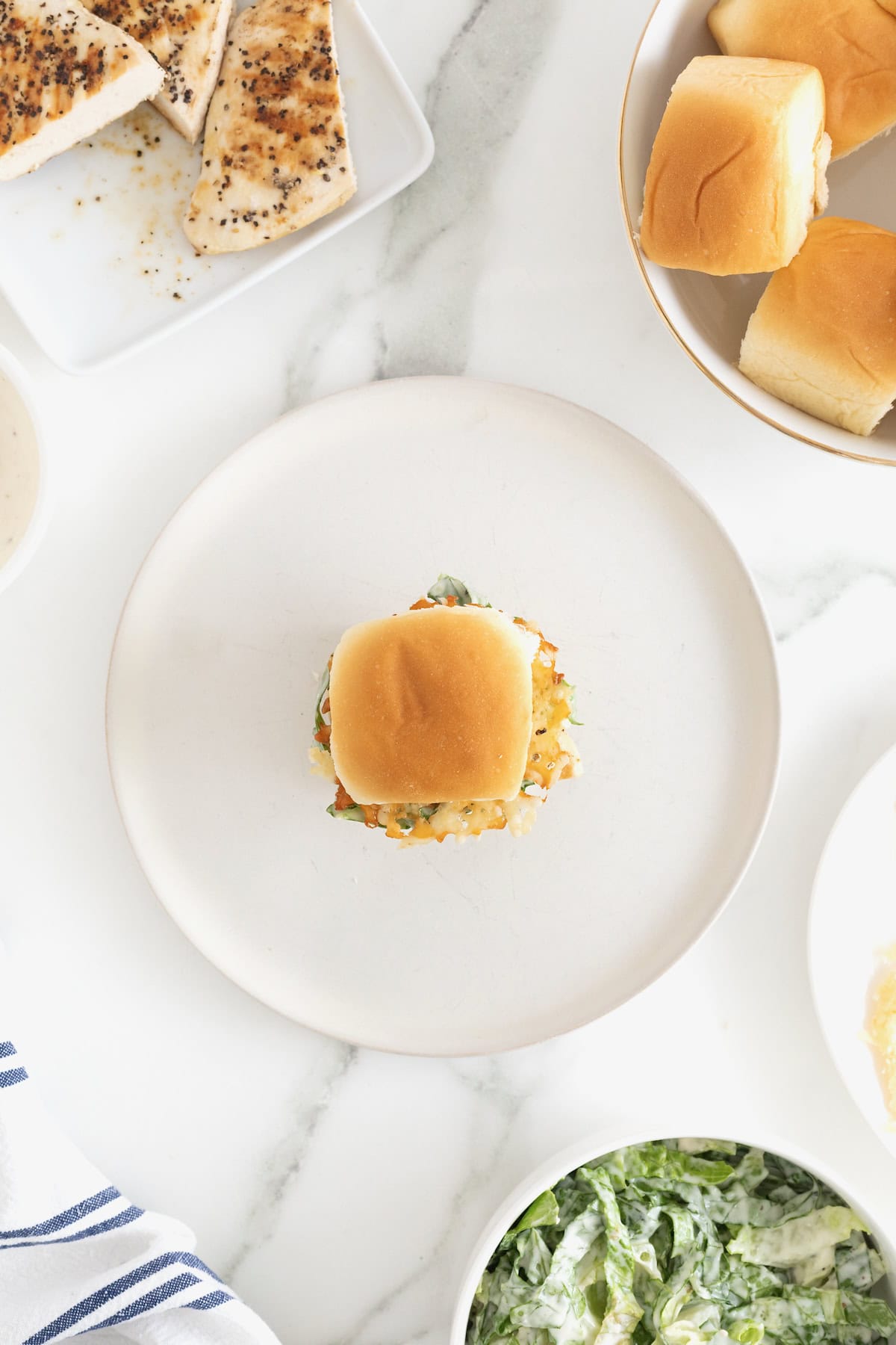 A grilled chicken caesar slider on a white plate.