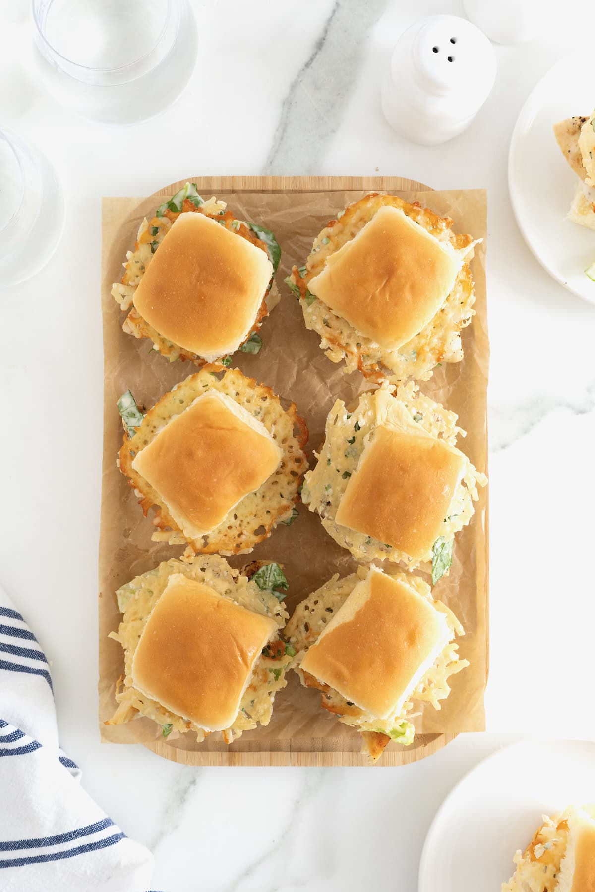 Six grilled chicken caesar sliders on a wooden cutting board. 