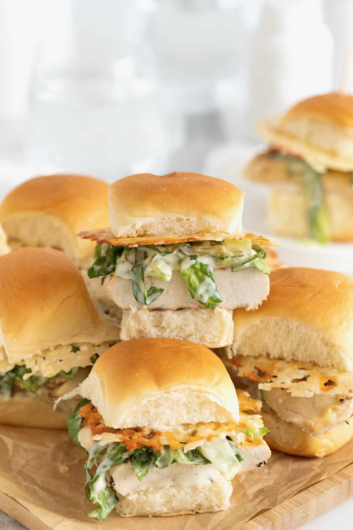 A pile of grilled chicken caesar sliders on a cutting board.