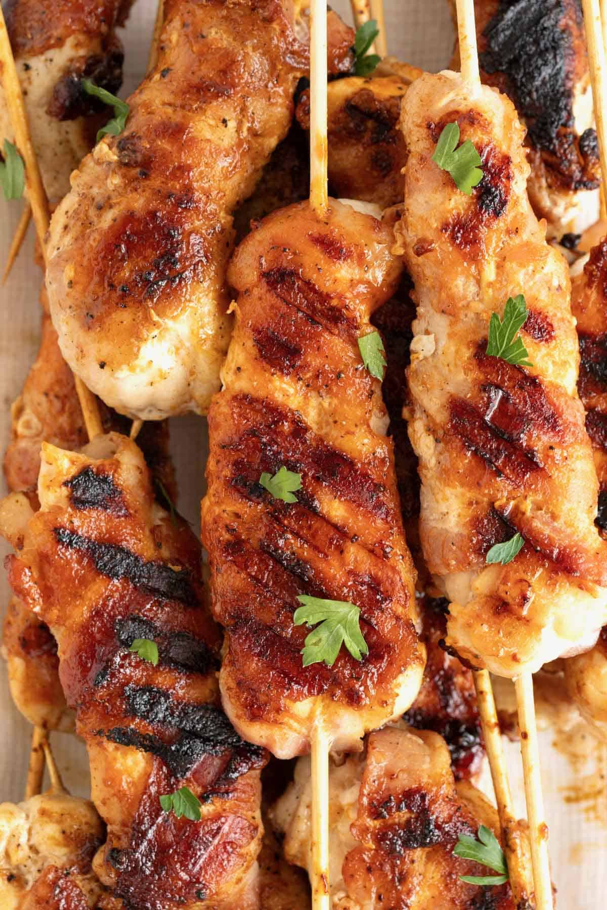 A pile of bacon-wrapped grilled chicken tenderloins.
