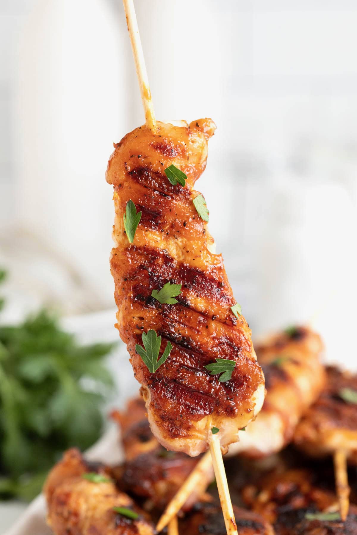 A bacon wrapped chicken tender on a wooden skewer.