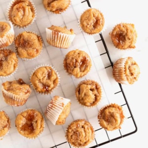 Peanut butter and jelly muffins lying on a parchment lined metal cooling rack.