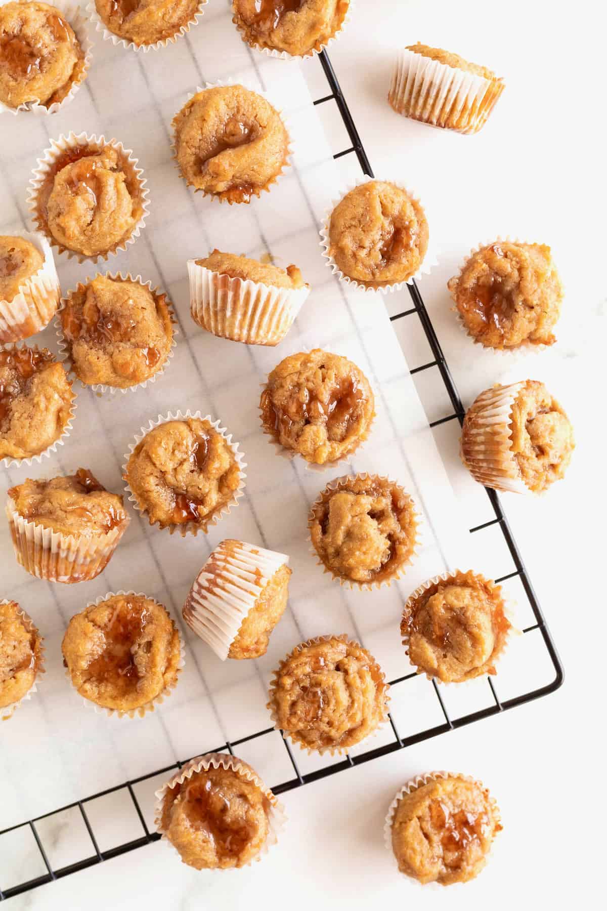 Peanut butter and jelly muffins lying on a parchment lined metal cooling rack. 