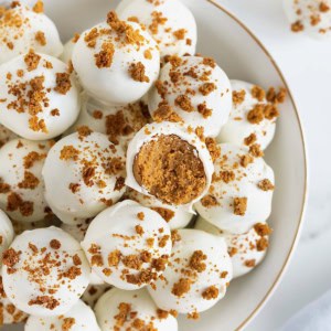 A large white gold-rimmed serving dish filled with pumpkin spice cake balls.