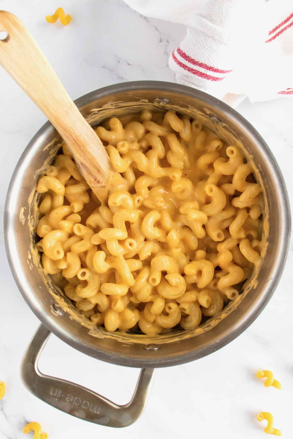 a pot of stovetop macaroni and cheese with a wooden spoon in it.