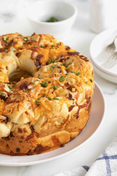 A bacon and cheddar monkey bread on a large white plate.
