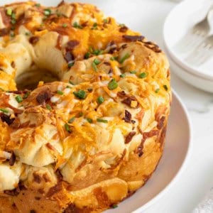 A bacon and cheddar monkey bread on a large white plate.