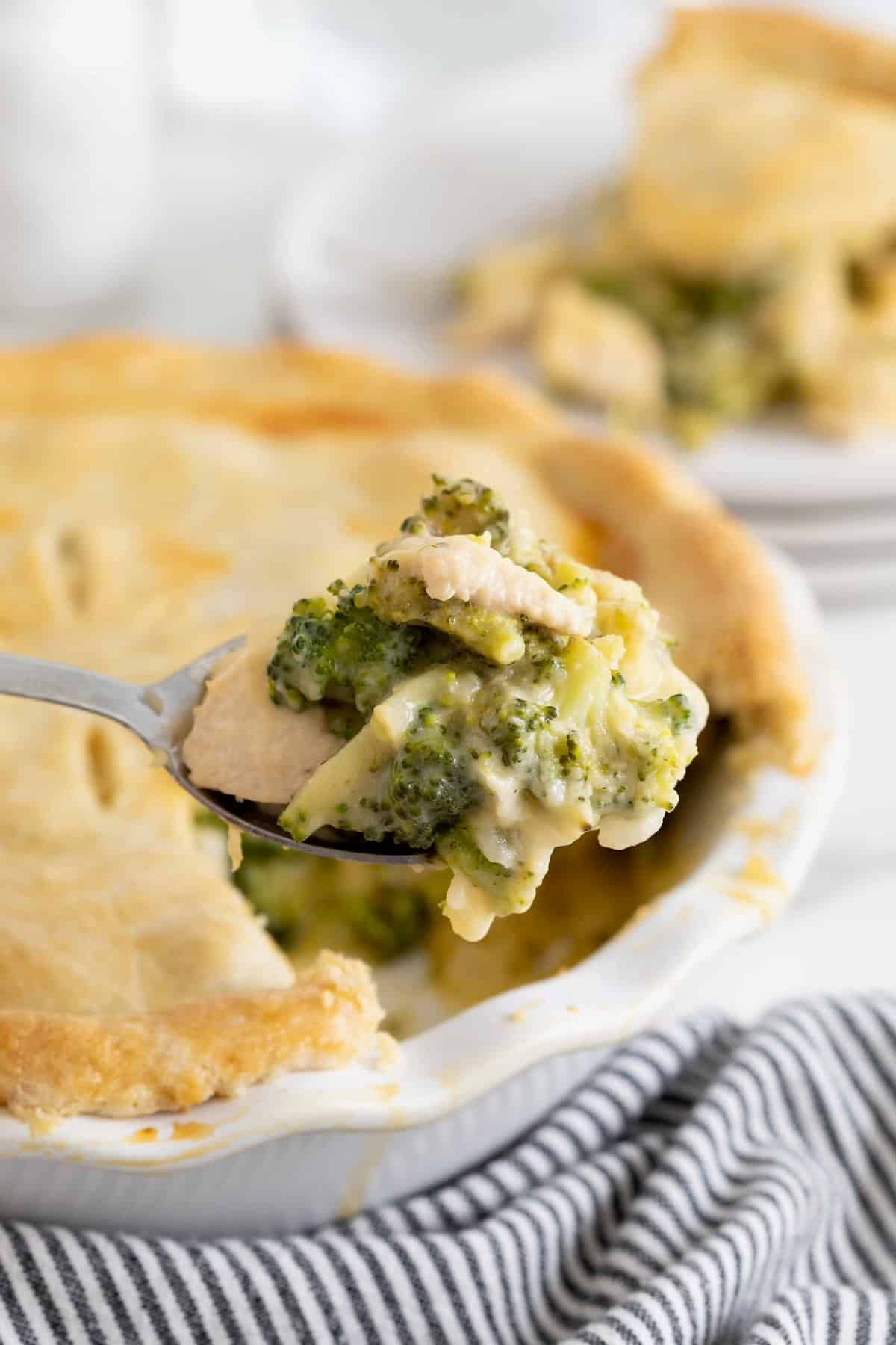 A spoonful of cheesy broccoli pot pie on a serving spoon.