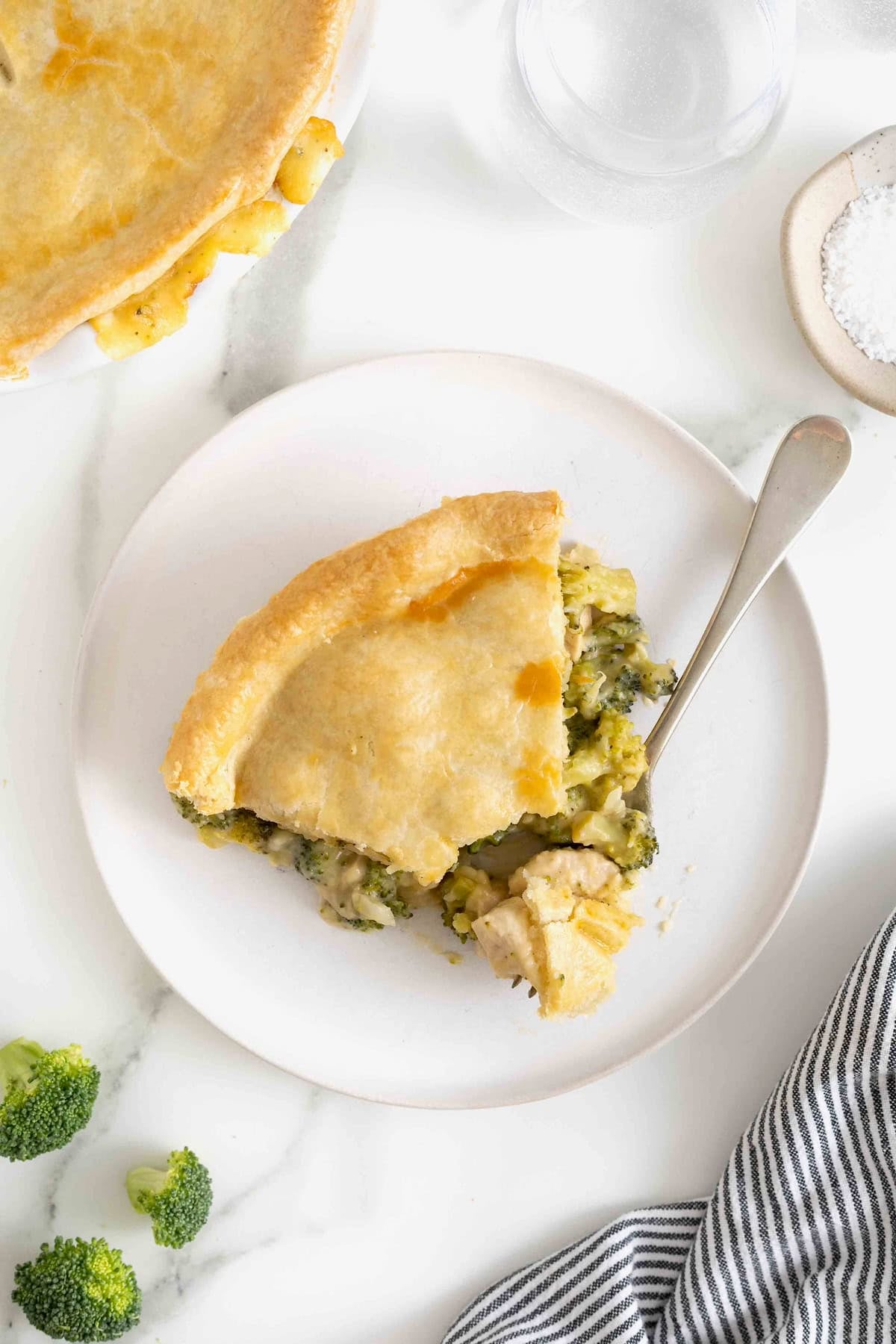 A serving of broccoli pot pie on a white plate with a fork.