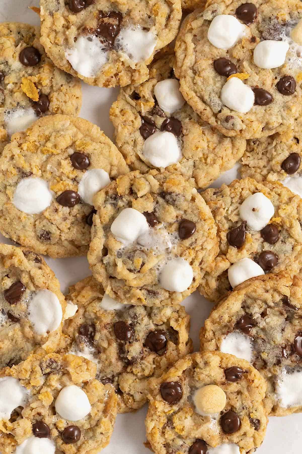 A pile of corn flake cookies with chocolate chips, mini marshmallows and coconut.