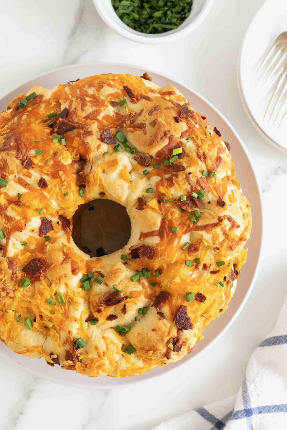 A bacon and cheddar monkey bread on a large white plate.