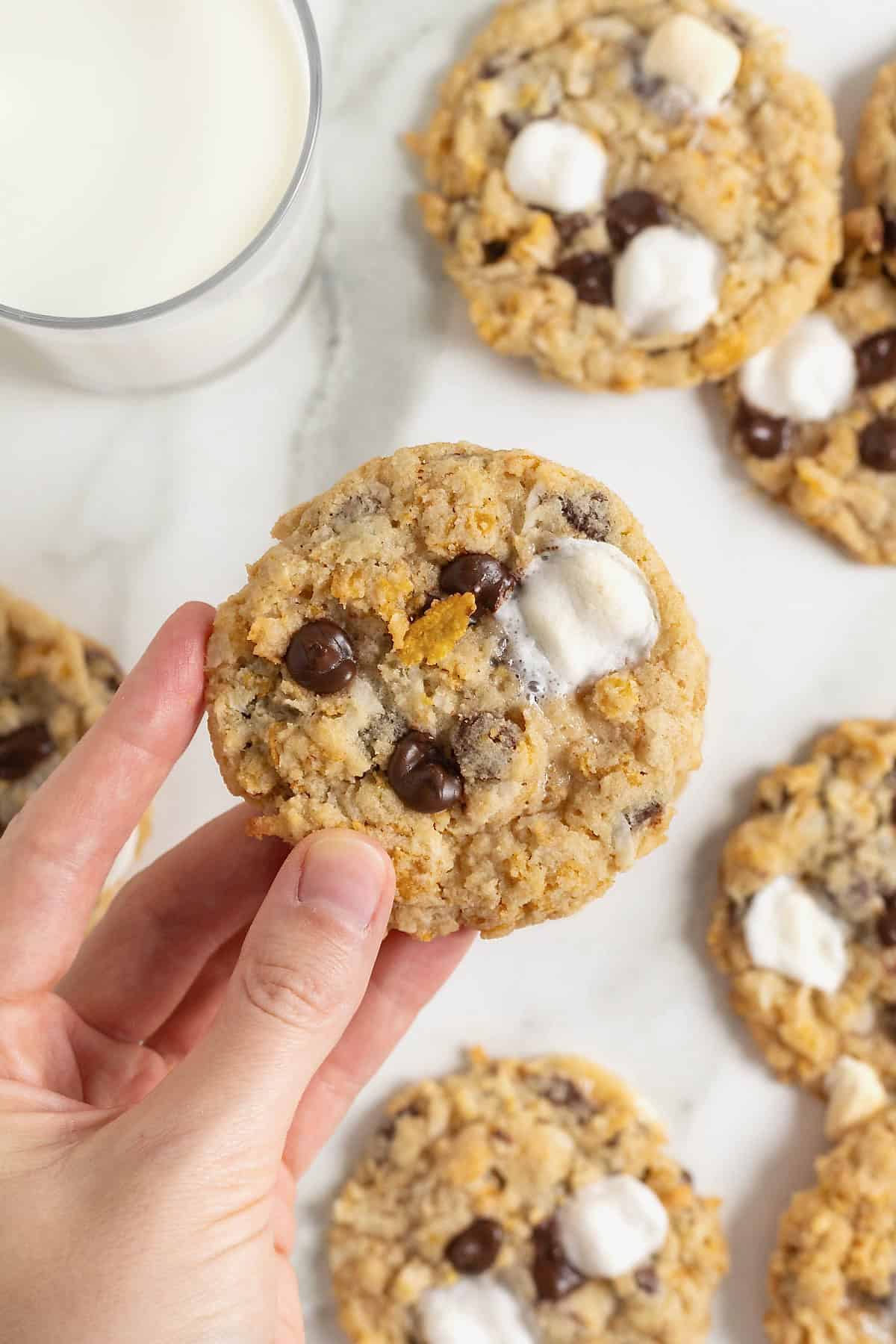 A hand holding a corn flake chocolate chip cookie.