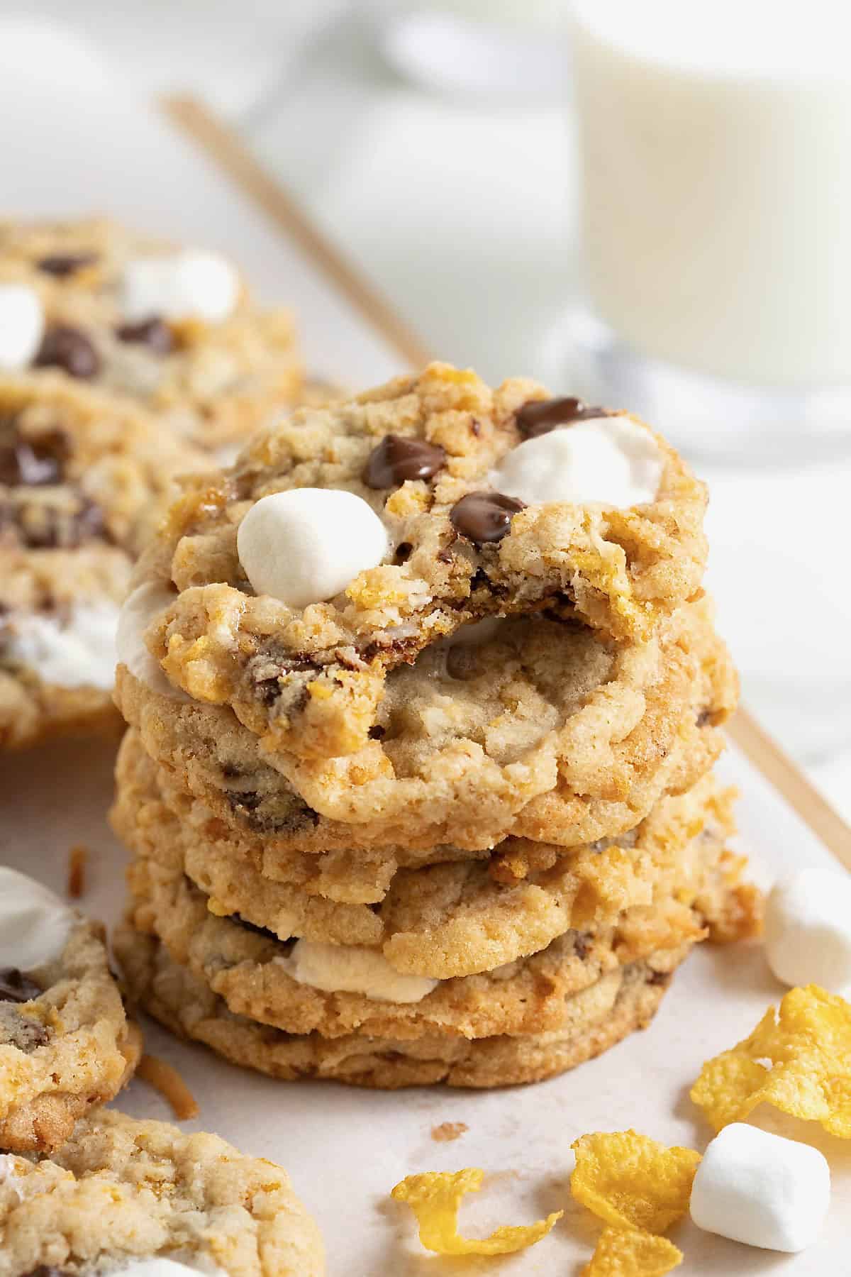 A stack of corn flake coconut marshmallow chocolate chip cookies. The top cookie has a bite out of it.