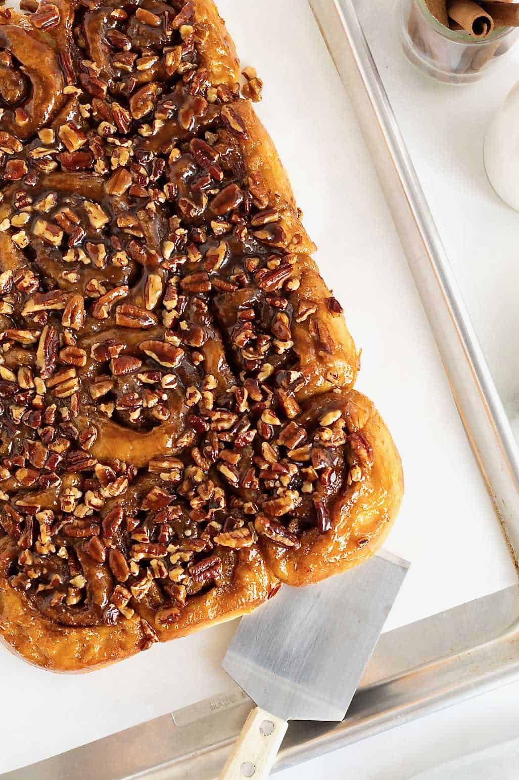 Sticky buns on a parchment lined aluminum baking sheet.