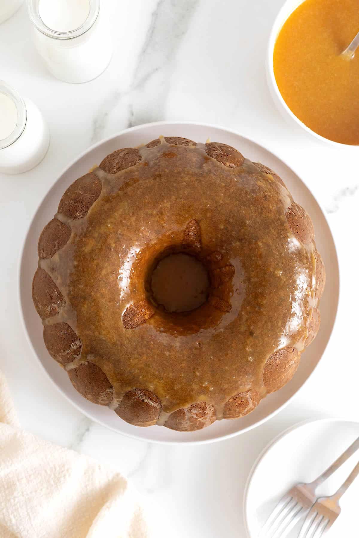 A pound cake drizzled with caramel sauce on a large white platter.