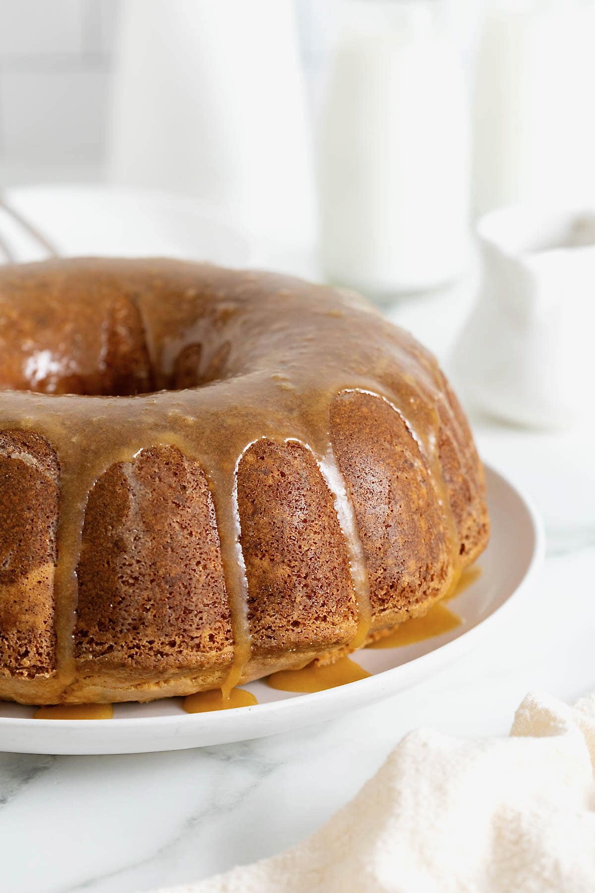 A pound cake drizzled with caramel sauce on a large white platter.
