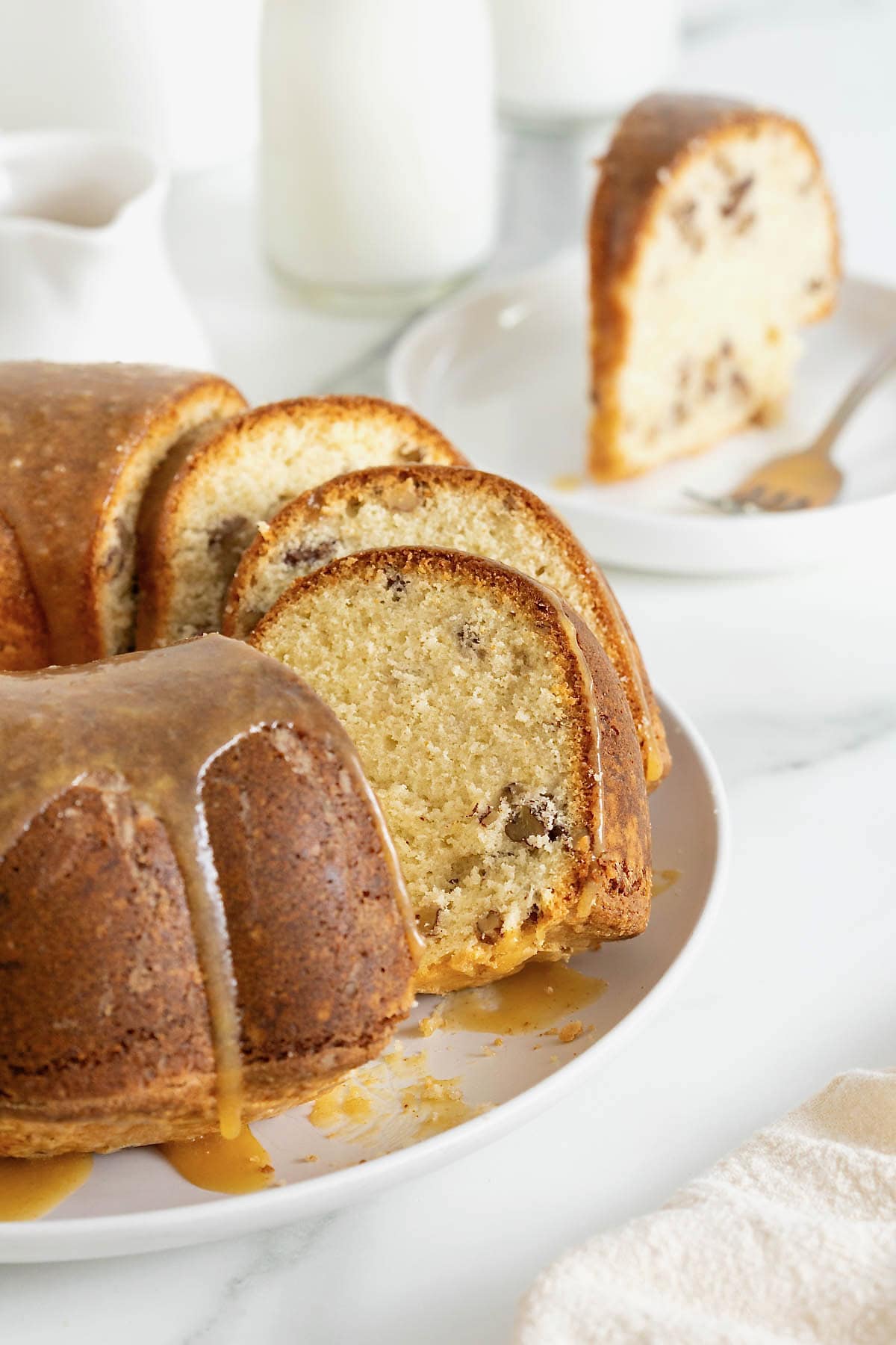 A pecan pound cake cut into several slices on a white cake plate. 