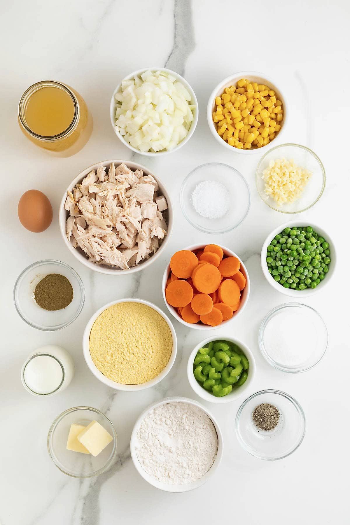 Ingredients to make turkey and cornbread dumplings in small glass dishes on a white marble counter.