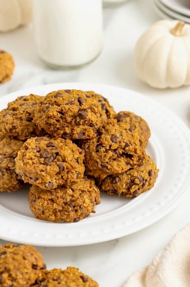 A white round serving platter of mini pumpkin chocolate chip oatmeal cookies.