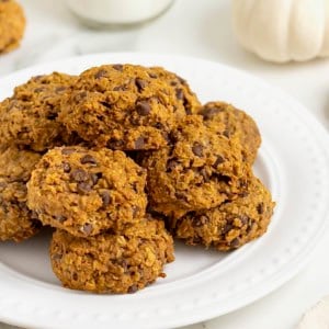 A white round serving platter of mini pumpkin chocolate chip oatmeal cookies.