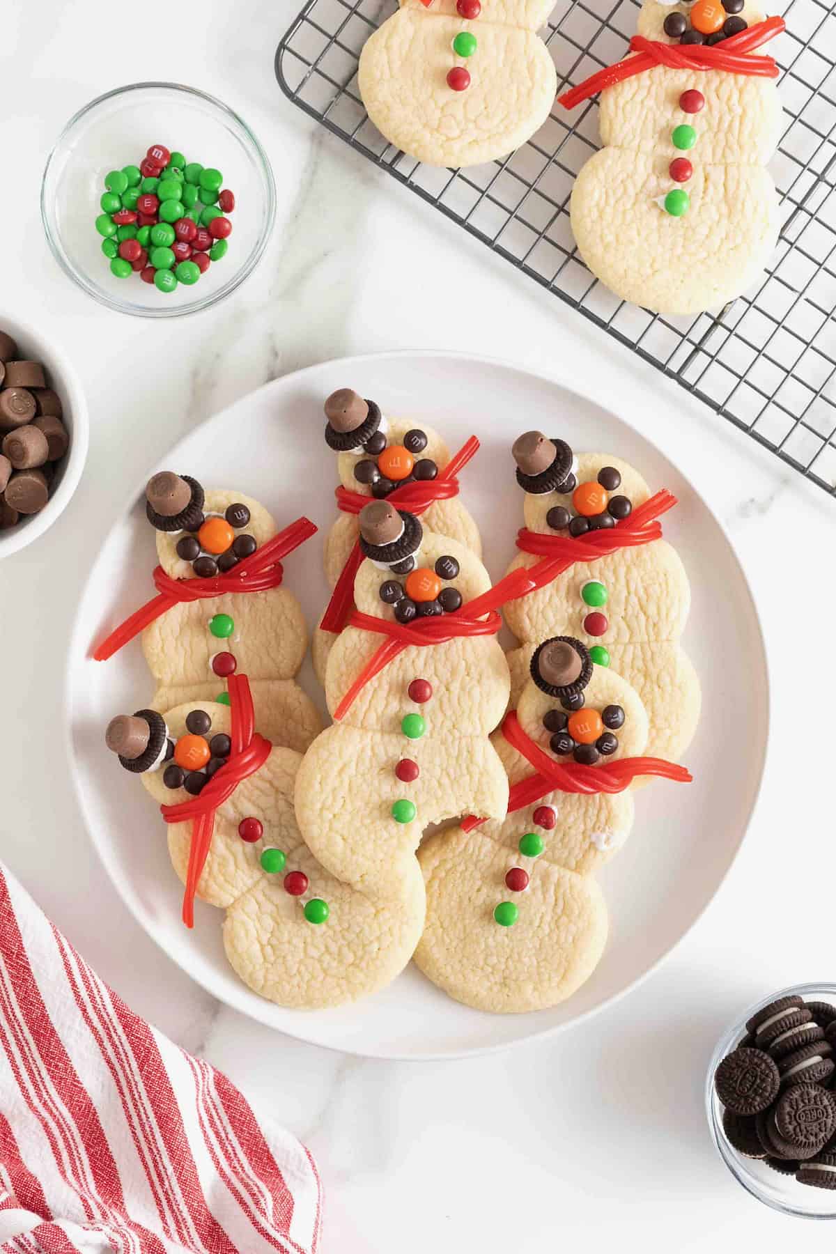 Six snowman sugar cookies on a large white plate.