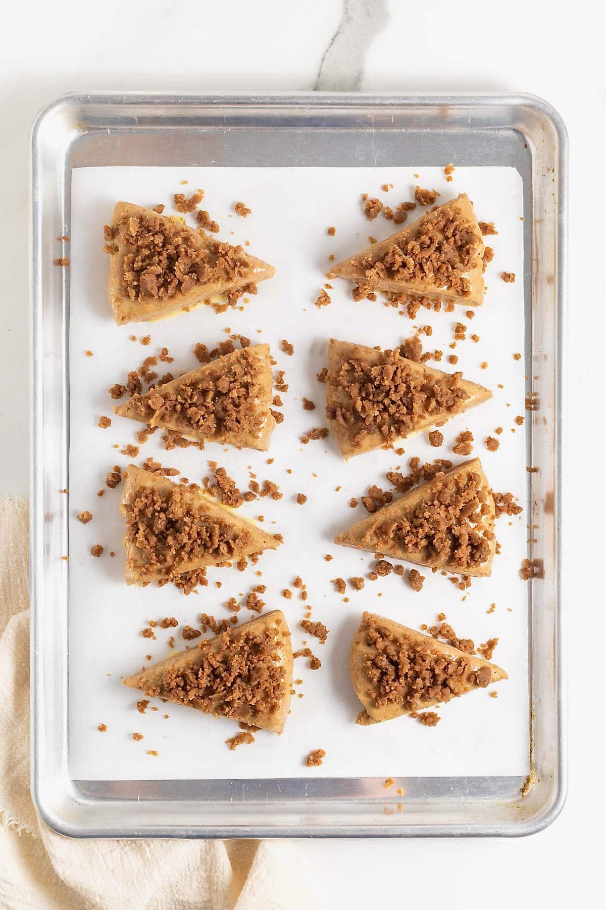 Streusel on scones on a parchment lined baking sheet.