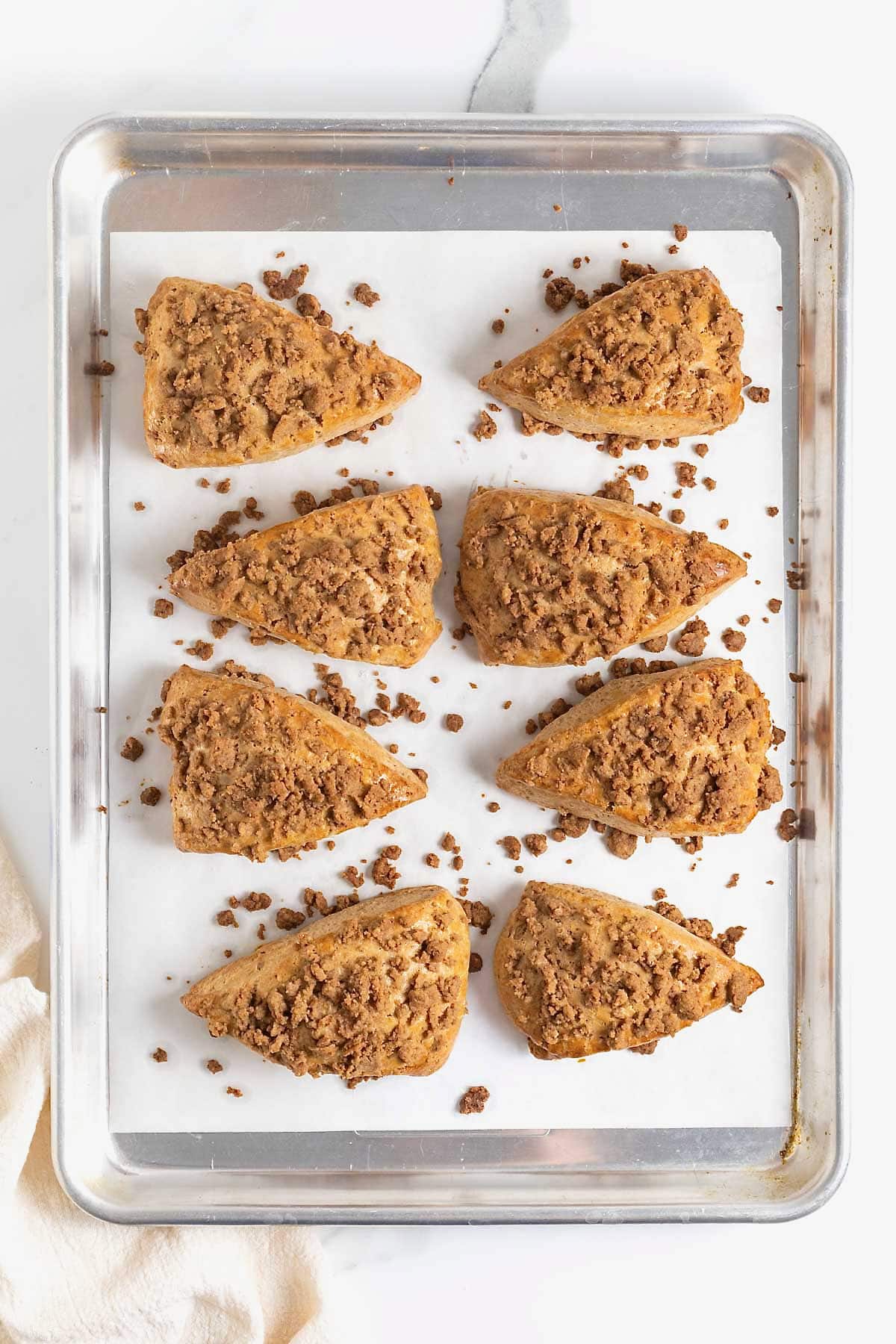 Eight snickerdoodle streusel scones on a parchment lined baking sheet.
