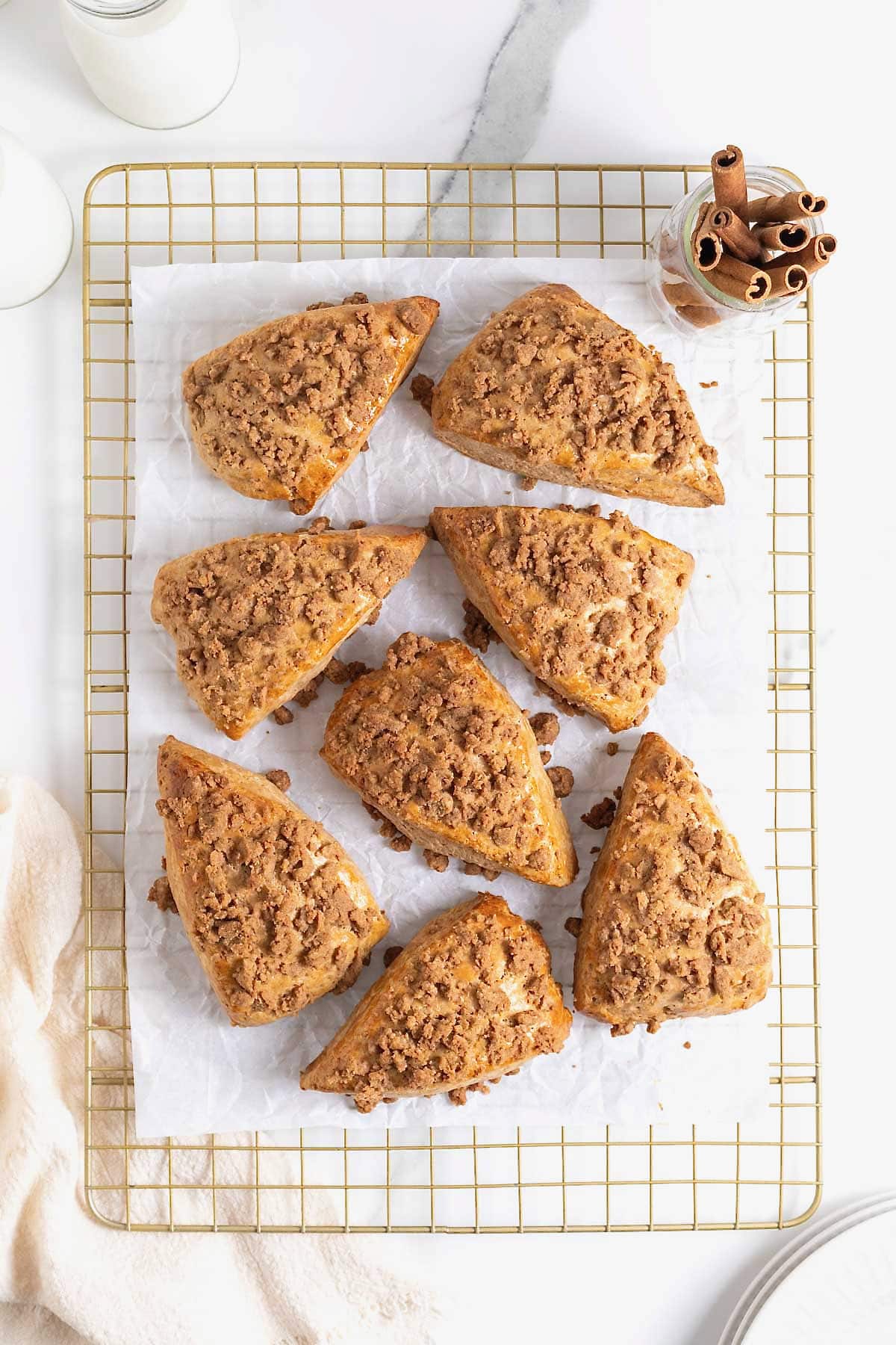 Eight snickerdoodle streusel scones on a parchment lined gold-toned cooling rack.