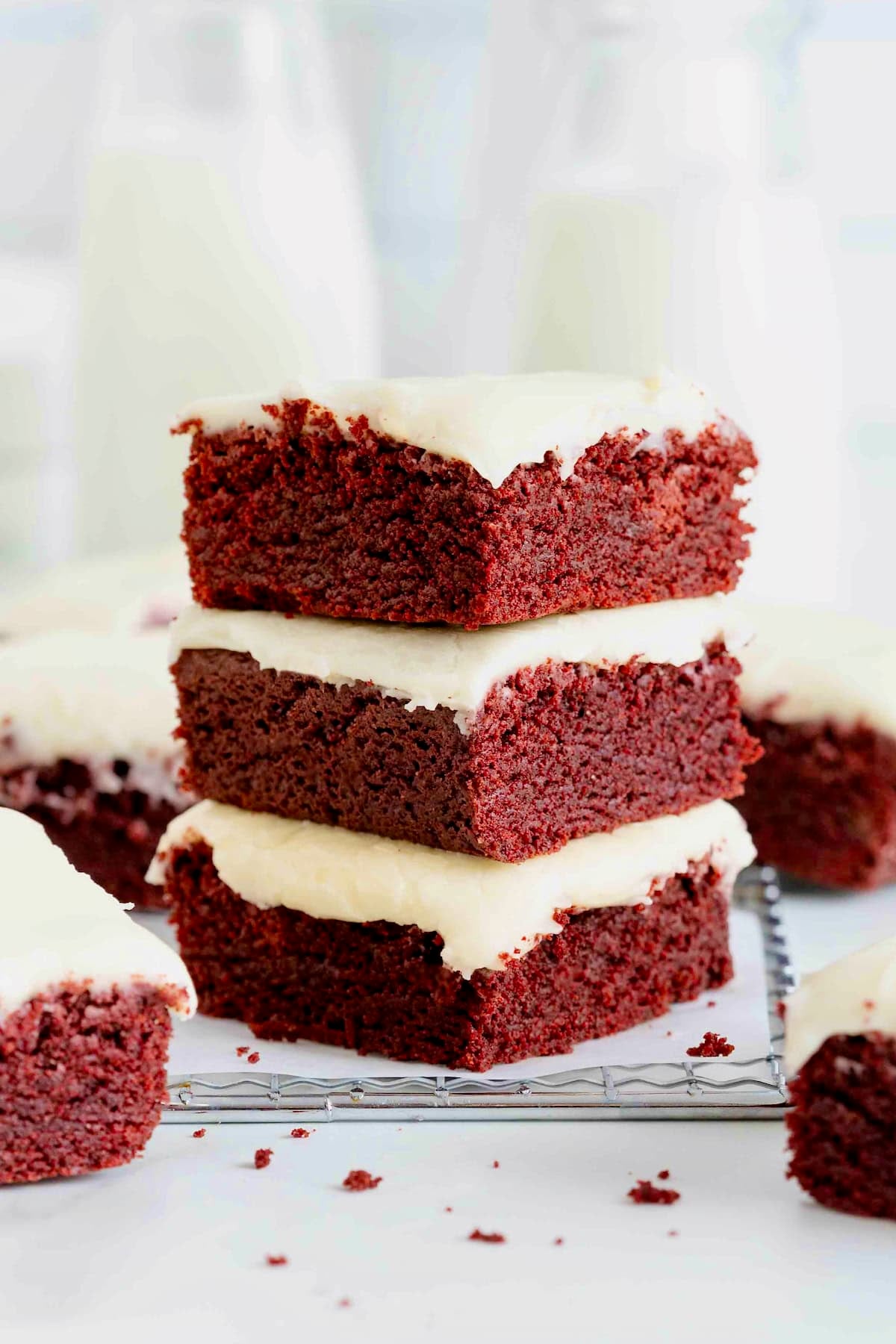 A stack of three red velvet brownies with white frosting.