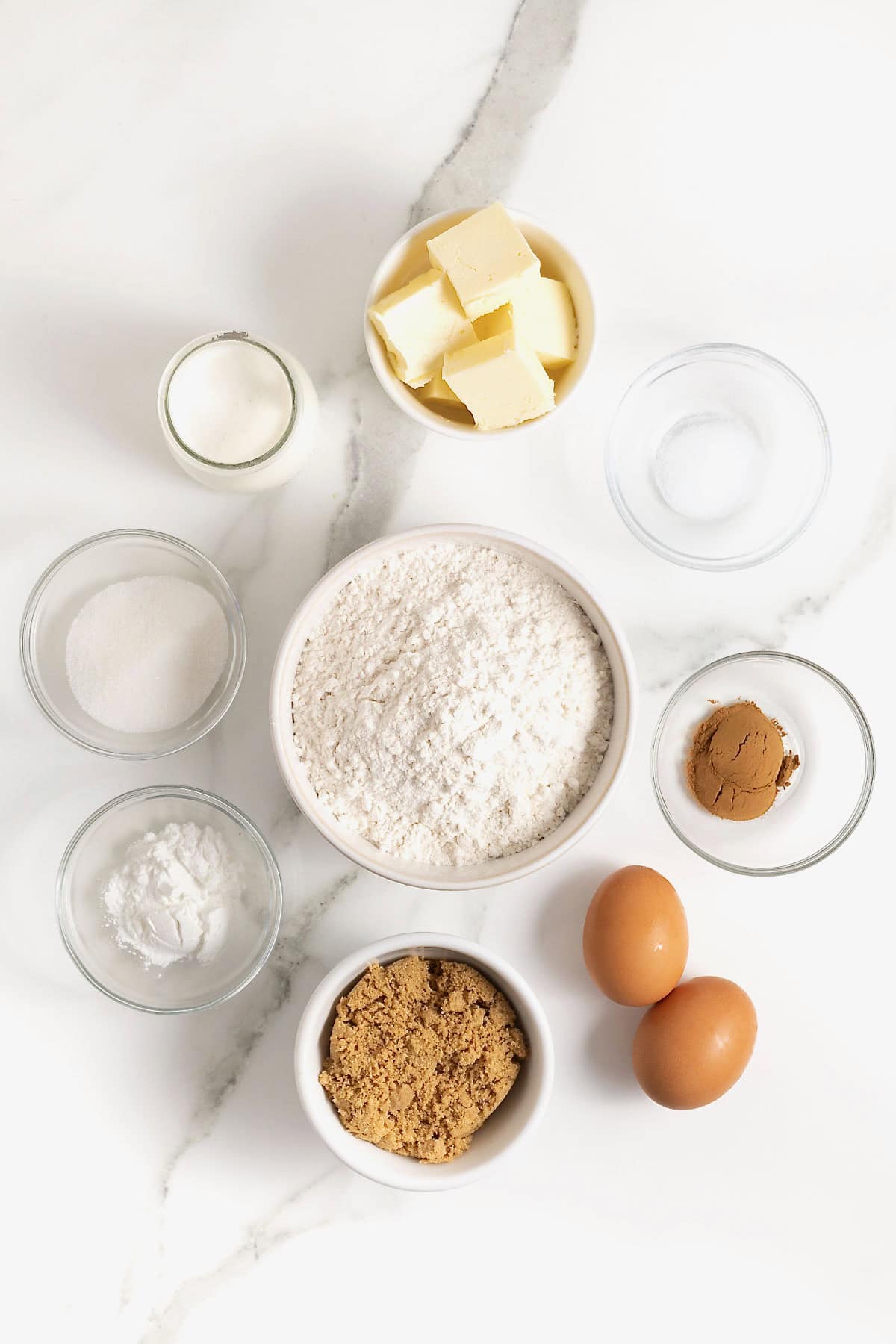 Ingredients to make snickerdoodle scones in small glass dishes on a white marble counter.