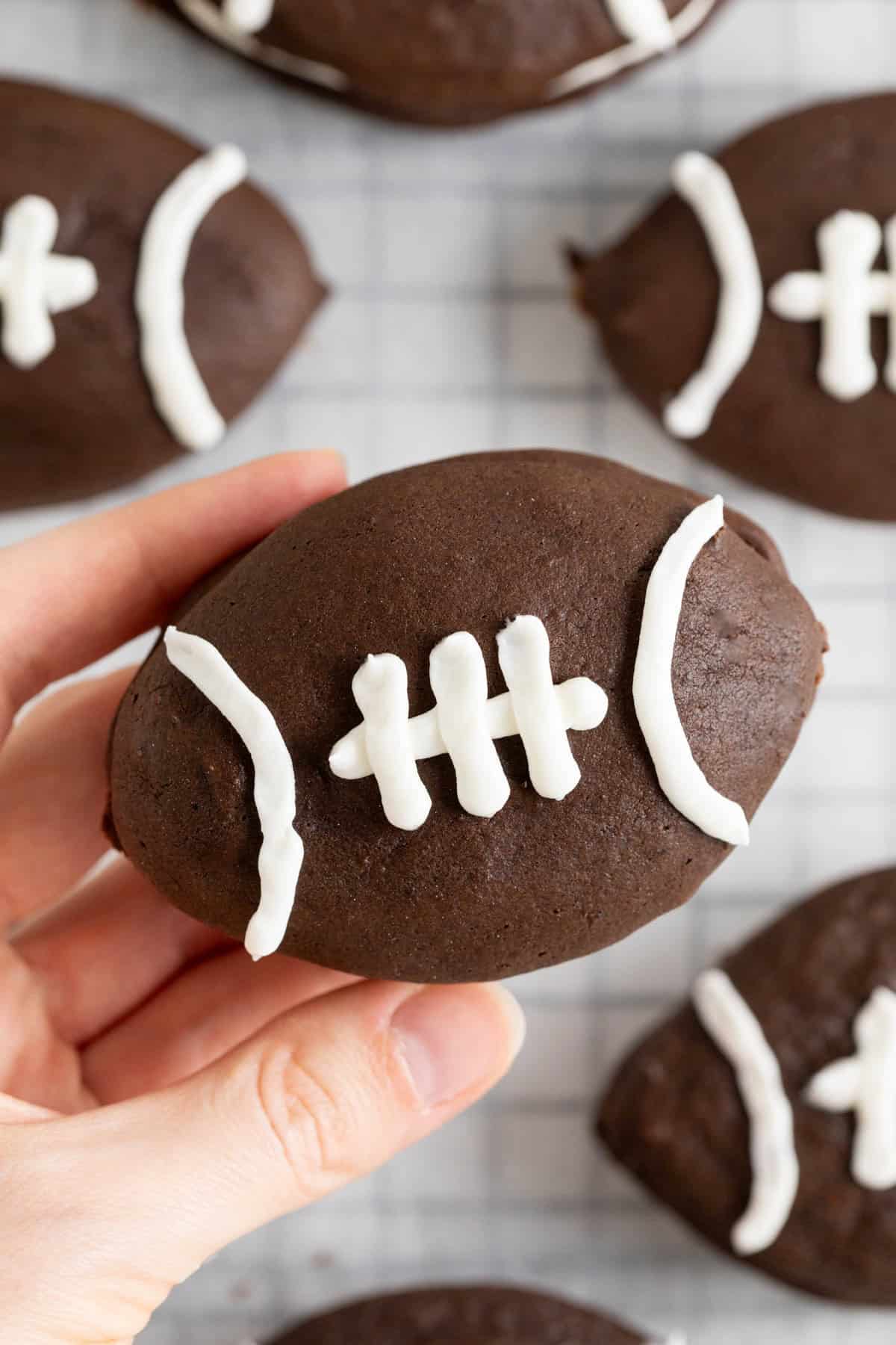A hand holding a football shaped whoopie pie.