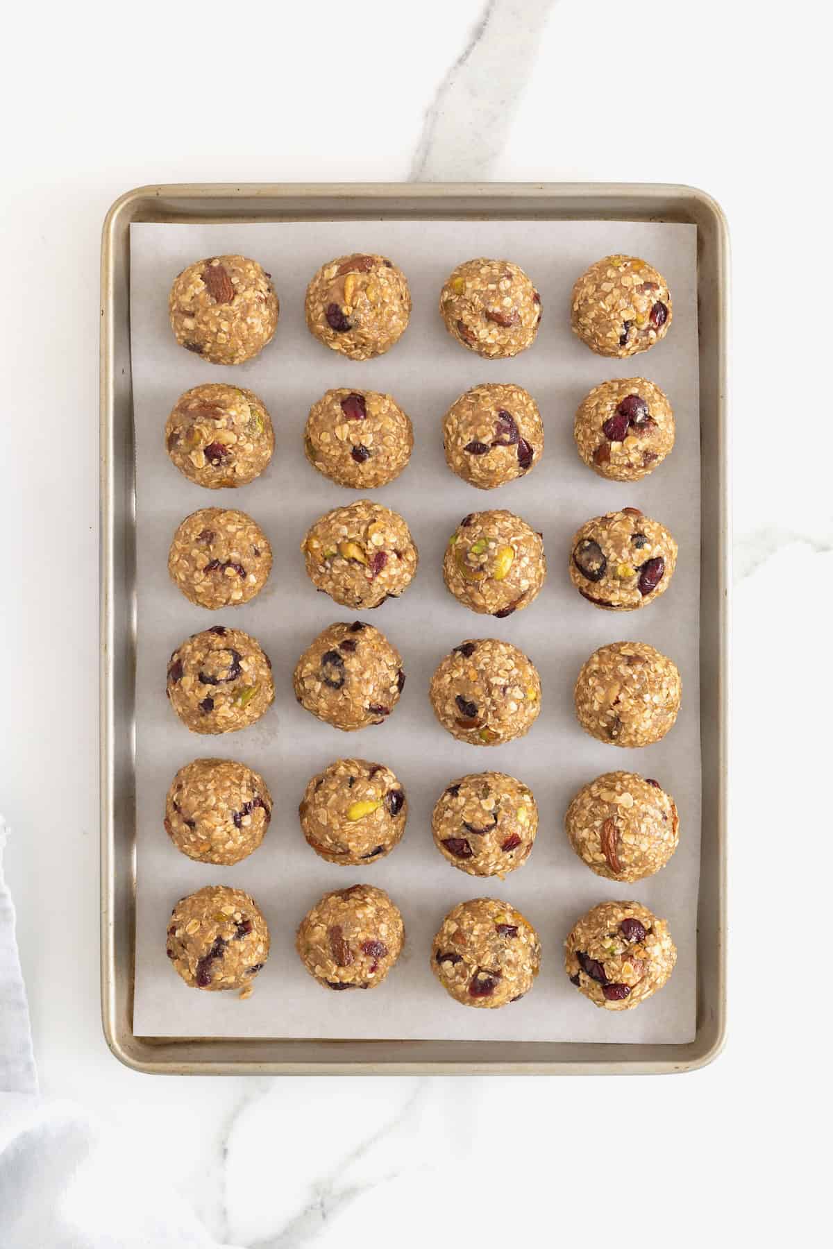 A parchment lined baking sheet with 24 trail mix bites.