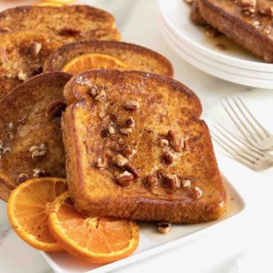 Orange pecan baked French toast on a white rectangular serving platter.