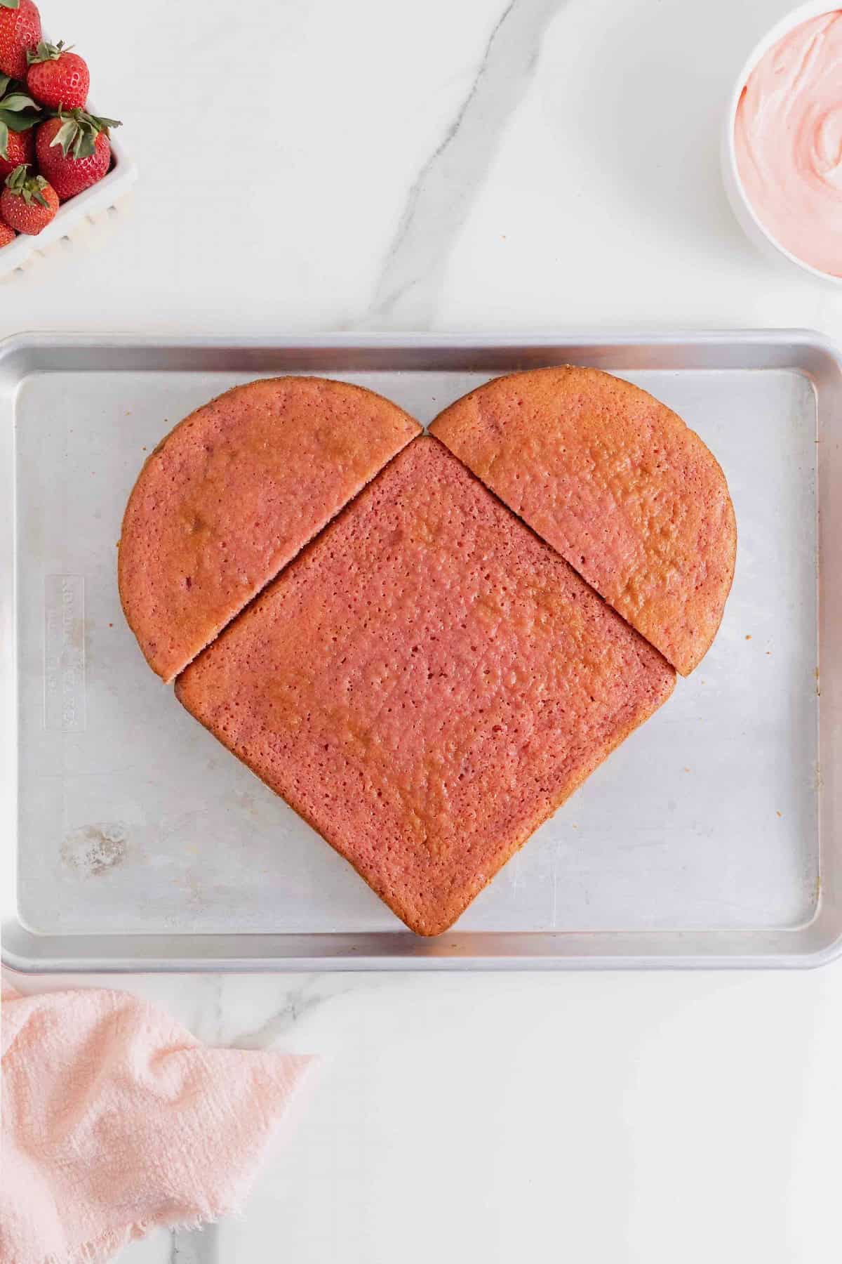 A pink square cake and two halves of a round cake arranged to look like a heart.